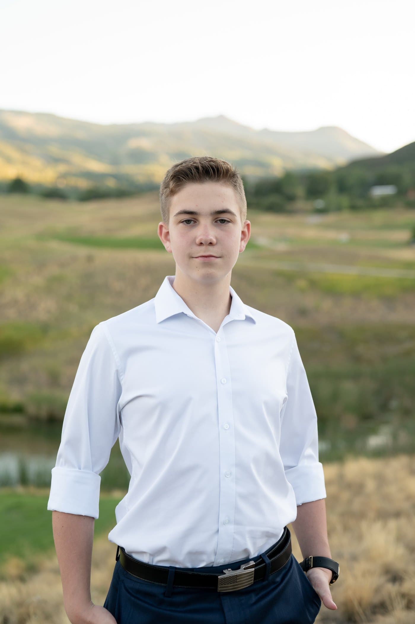 Michael as a high school freshman standing in a white button-down shirt in front of hills at sunset